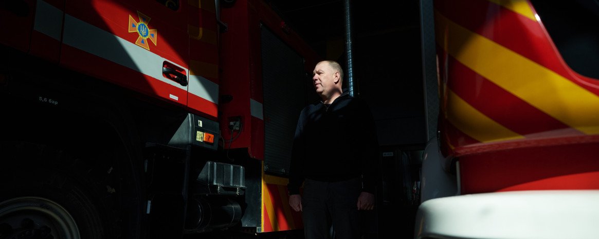 Чоловік між пожежними машинами.