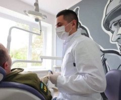 військовослужбовець у стоматологічному кріслі та стоматолог в білому халаті та масці