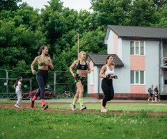 три дівчини біжать на стадіоні