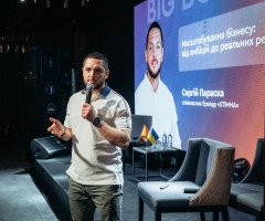 Співзасновник бренду Stimma стоїть на сцені з мікрофоном у руках, позаду великий екран.