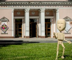 Дерев'яна лялька-маріонетка на тлі театру ляльок
