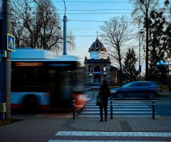 Динамічна вулиця з громадським транспортом, людьми та церквою на горизонті.
