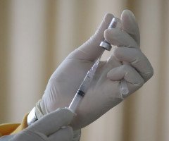 лікар в білих рукавичках готується зробити вакцинацію