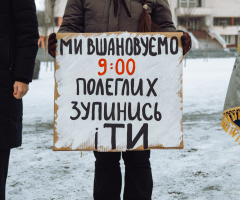 людина в темному одязі тримає плакат