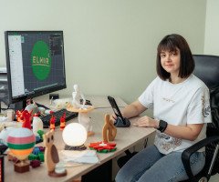 Жінка за комп'ютером з 3D-світильниками на столі.