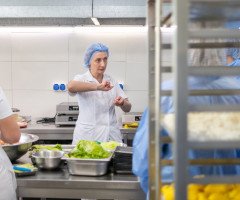 Жінки у білій формі на промисловій кухні.