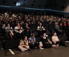 Люди сидять у залі на форумі.