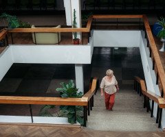 Сходовий майданчик, по якому підіймається світловолоса жінка.