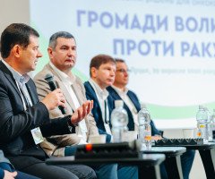 Чоловіки з мікрофонами на тлі банеру «Громади - Волині проти раку».