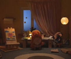 Ляльковий будиночок у вигляді дитячої кімнати з лялькою за столом.