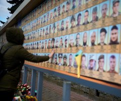 жінка біля стенду памяті героїв