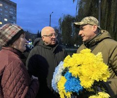 Військовослужбовець з квітами спілкується з чоловіком та жінкою