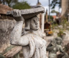 Скульптура жінки, що тримає тацю на голові. На фоні подвір'я будинку скульптора Миколи Голованя.