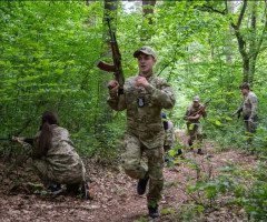 хлопець біжить із автоматом у лісі