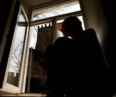 Силует дівчини на на підвіконні з видом на Луцький замок з вікна.