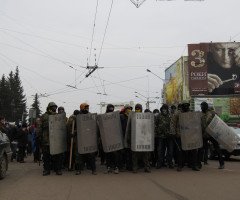 Чоловіки в балаклавах, касках та з міліцейськими металевими щитами стоять на проїжджій частині проспекту Волі у Луцьку.