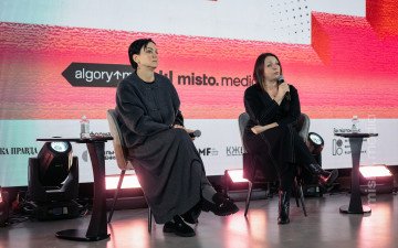 дві людини сидіть з мікрофонами на сцені