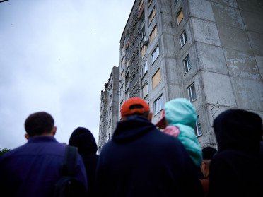 Люди біля зруйнованого після атаки у ніч на 6 червня будинку.