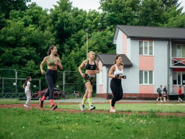 три дівчини біжать на стадіоні