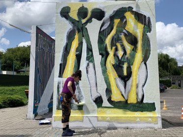 художниця замальовує стіну галереї