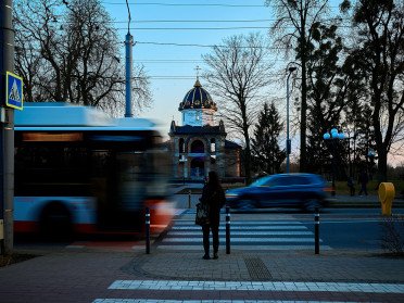 Храм Холмської ікони Божої Матері. Динамічна вулиця з громадським транспортом, людьми та церквою на горизонті.