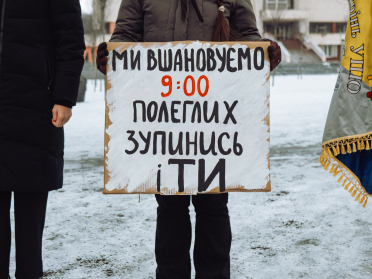 людина в темному одязі тримає плакат