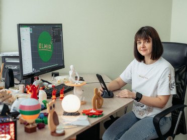 Жінка за комп'ютером з 3D-світильниками на столі.