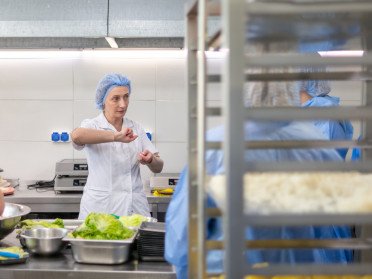 Жінки у білій формі на промисловій кухні.