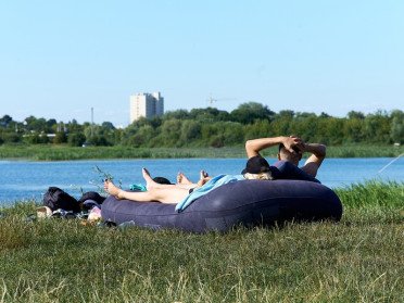 люди біля водойми лежать на матраці
