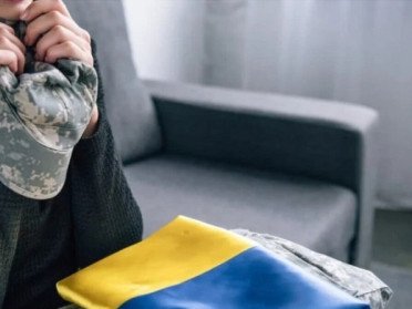 жінка з формою військового та прапором