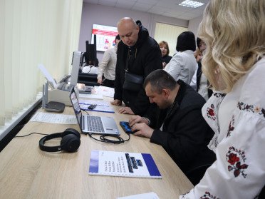 Чоловік сидить за ноутбуком з портативним дисплеєм Брайля