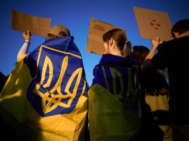 люди з прапорами на плечах з картонками в руках