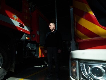 Чоловік між пожежними машинами.