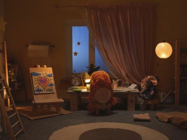 Ляльковий будиночок у вигляді дитячої кімнати з лялькою за столом.