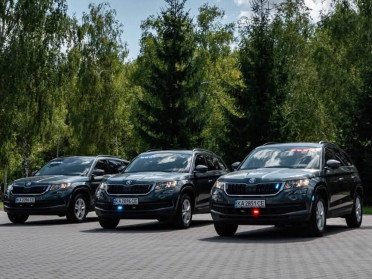 Три чорні автомобілі біля прапору України