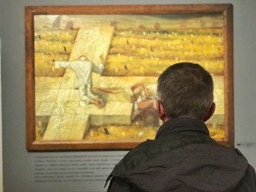 чоловік у музеї дивиться на картину Миколи Кумановського