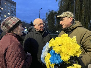 Військовослужбовець з квітами спілкується з чоловіком та жінкою