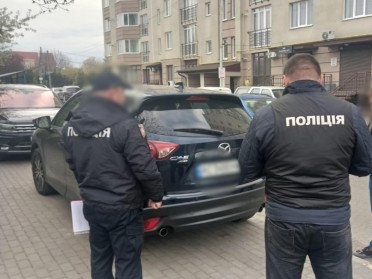 полвцейські стоять біля автомобіля.
