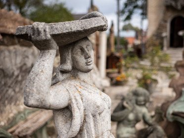 Скульптура жінки, що тримає тацю на голові. На фоні подвір'я будинку скульптора Миколи Голованя.