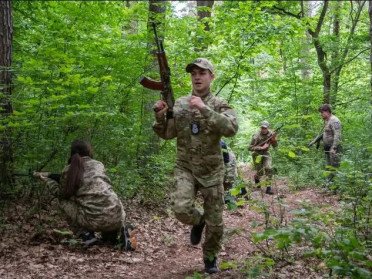 хлопець біжить із автоматом у лісі