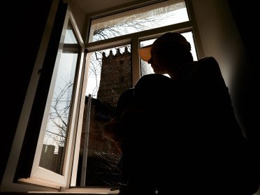 Силует дівчини на на підвіконні з видом на Луцький замок з вікна.