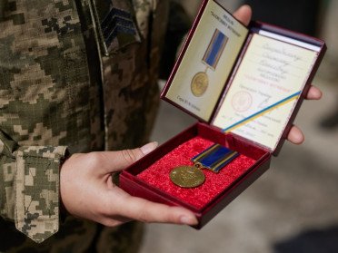 нагородна медаль та посвідчення до нього в руках військового