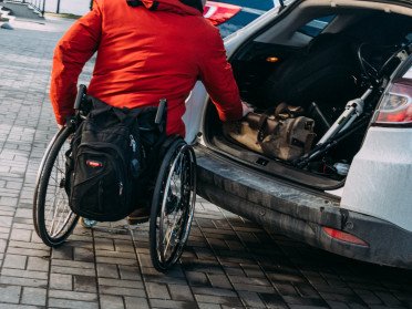 людина на колісному кріслі біля авто