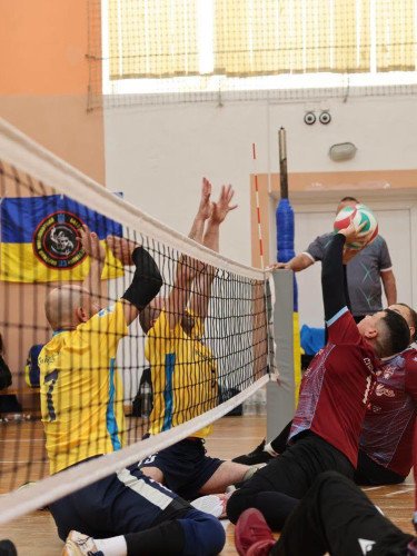 спортсмени грають у волейбол сидячи