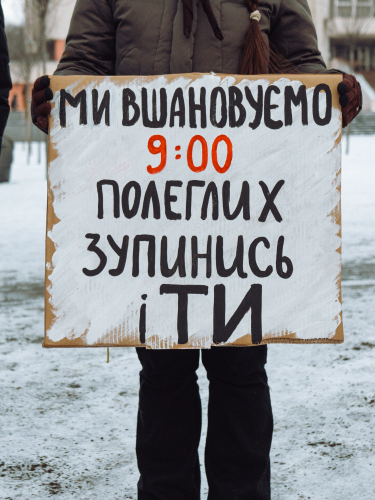 людина в темному одязі тримає плакат