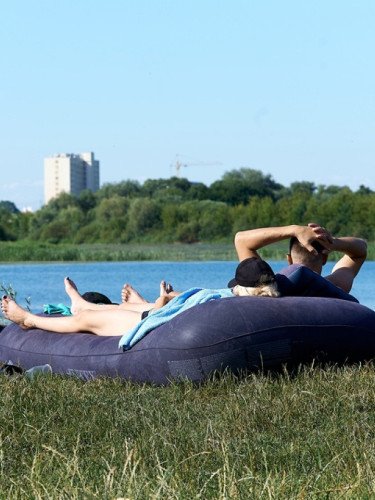 люди біля водойми лежать на матраці