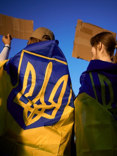 люди з прапорами на плечах з картонками в руках