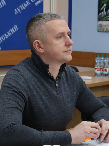 чоловік у сірому одязі сидить за столом