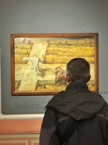 чоловік у музеї дивиться на картину Миколи Кумановського