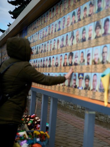 жінка біля стенду памяті героїв